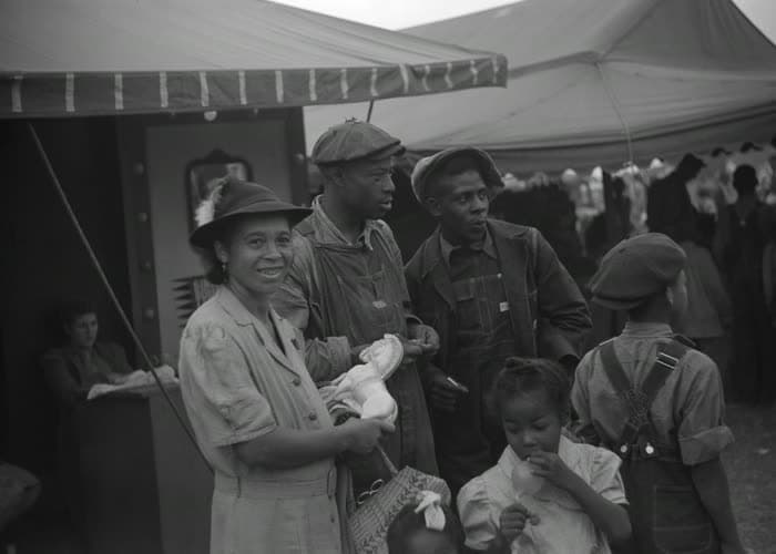 A family at a fairground stand, a baby held in her mother's arms