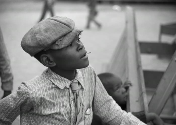 A boy in a flat cap, looking up at the rides