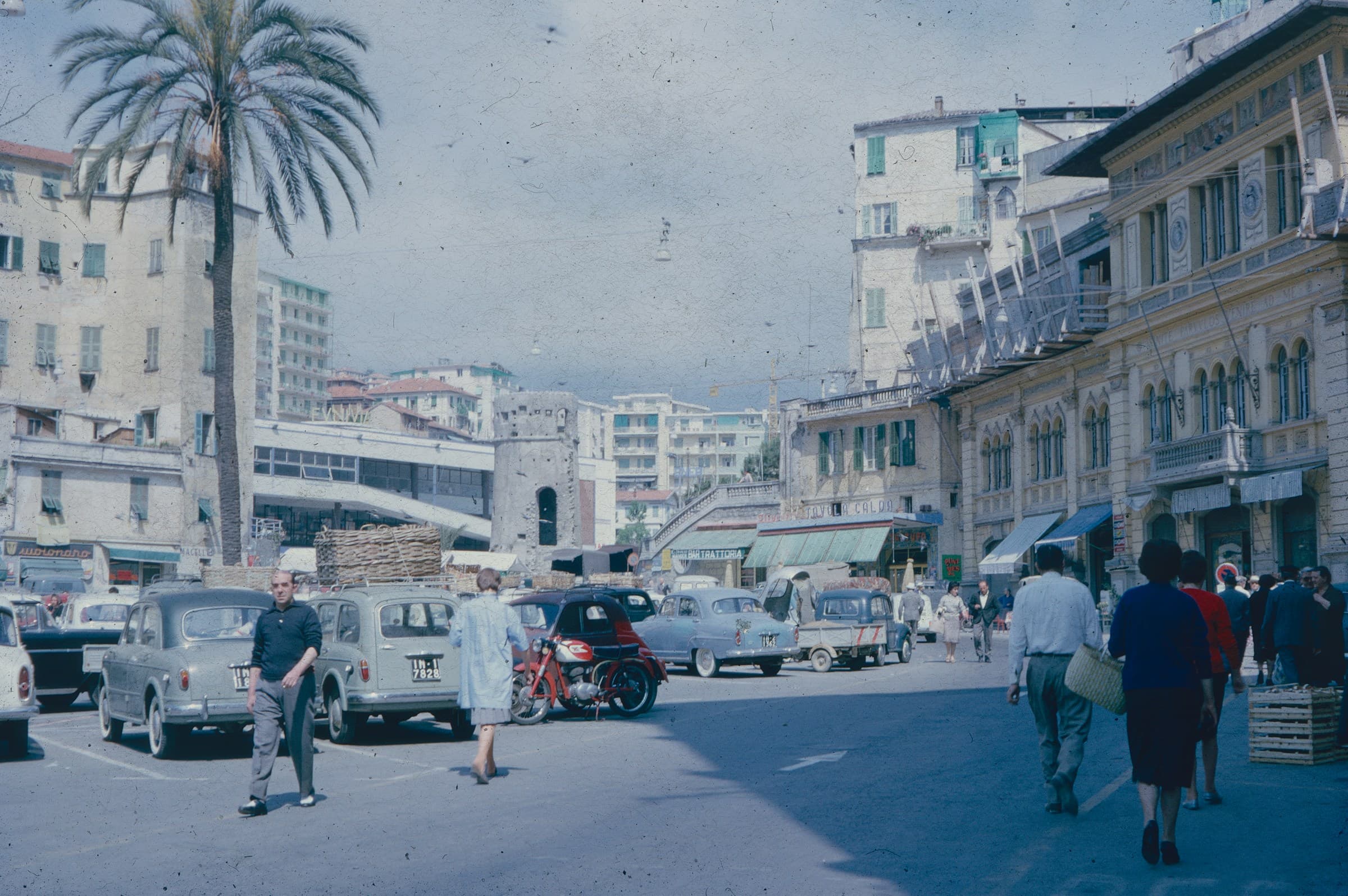 A busy Italian street, cars and shoppers of the period